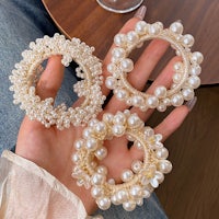 a woman is holding three pearls and a glass of wine