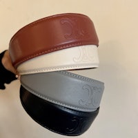 a person is holding a leather belt with a logo on it